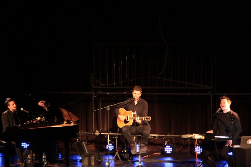 Trzech mężczyznz na scenie gra na różnych instrumentach