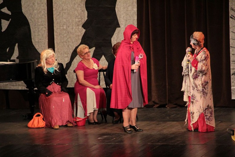 Na scenie stoi kobieta w czerwonym kapturku