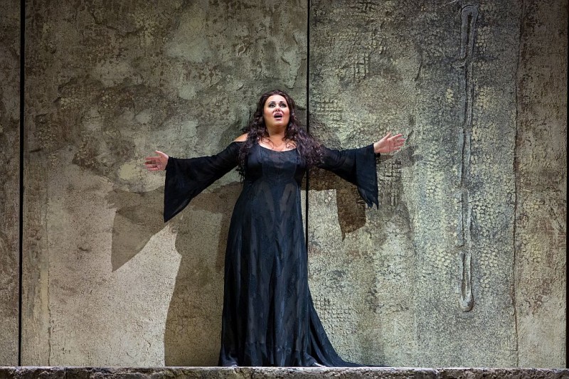 Kobieta w czarnej sukience stoi przy ścianie