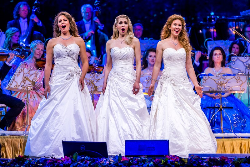 Trze kobiety w białych sukniach śpiewają na scenie
