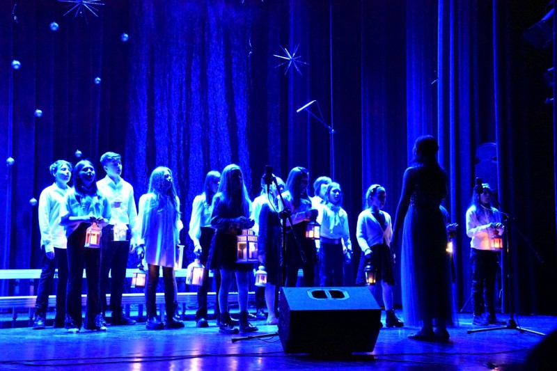 Zespół dziecięcy występuje na scenie, światła są przyciemnione.