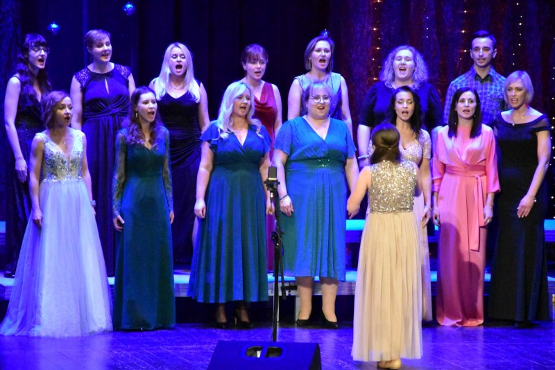 Kobiety w kolorowych sukienkach śpiewają kolędę