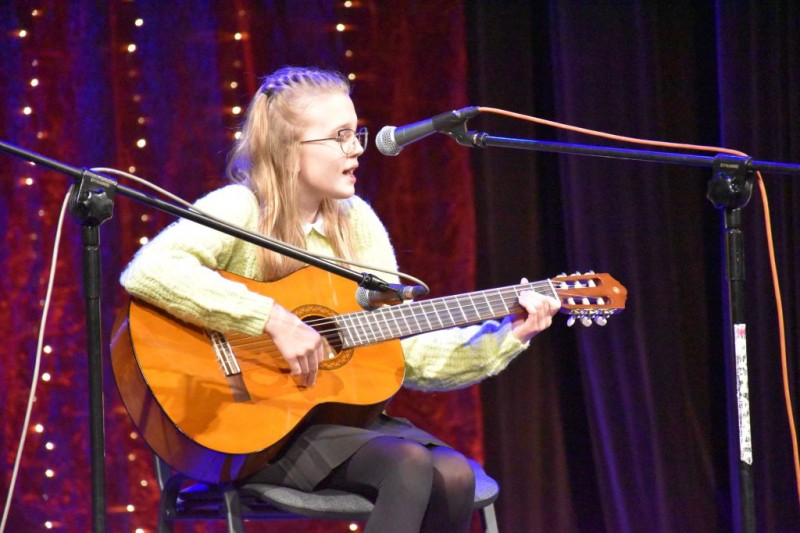 Występ dziewczynki śpiewającej i grającej na gitarze