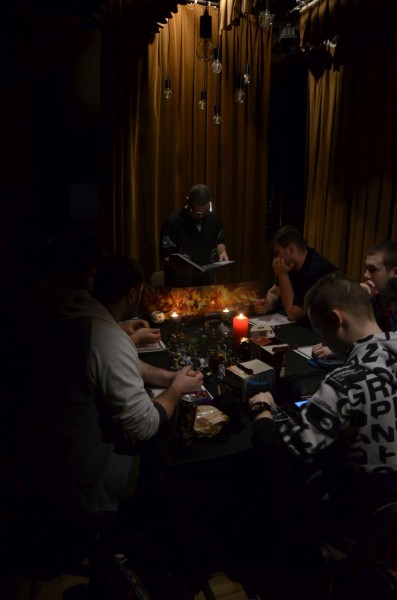 Mężczyźni siedzą przy stole na którym zapalone są świeczki