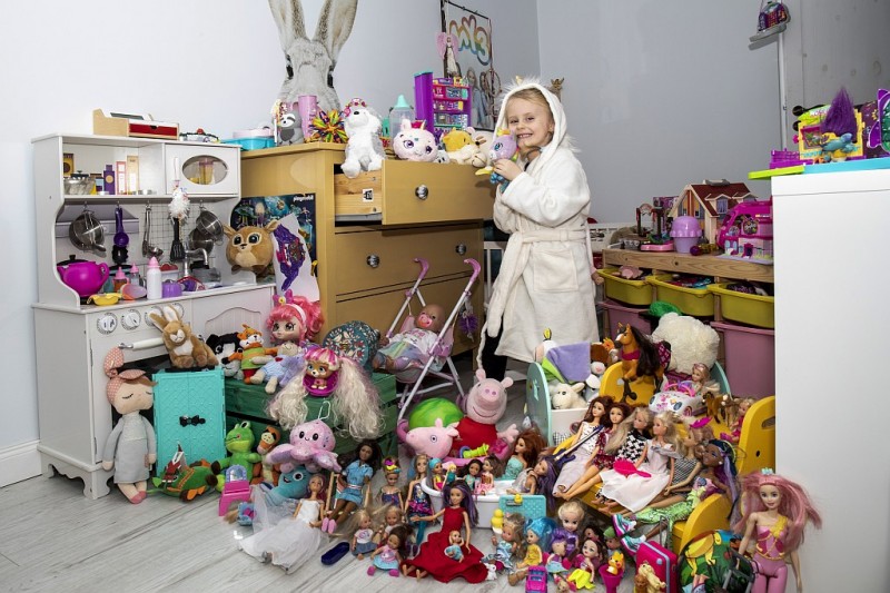 Dziewczynka w szlafroku stoi w pokoju pełnym zabawek