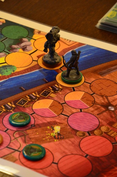 Plansza do gry na której stoją dwie figurki wojowników i dwa pionki