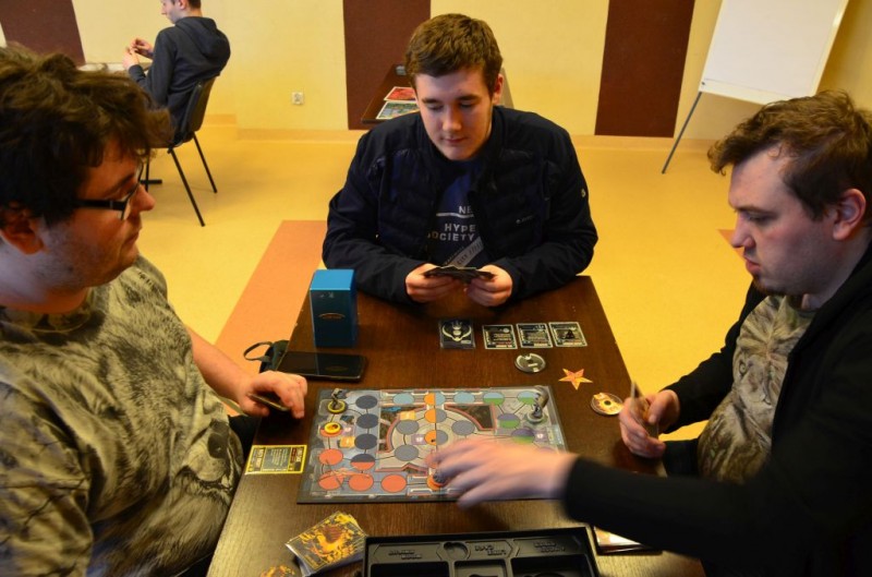 Trzech mężczzn gra przy stoliku w grę