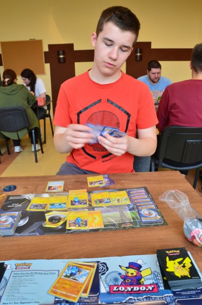 Chłopak w czerwonej koszulce trzyma w rękach karty do gry