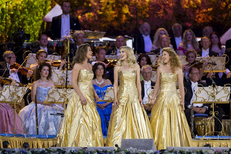 Trzy kobiety w złotych sukniach śpiewają arię