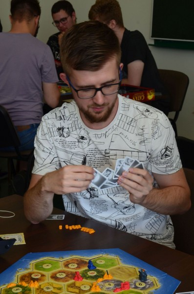 Mężczyzna w okularach trzyma w rękach karty do gry