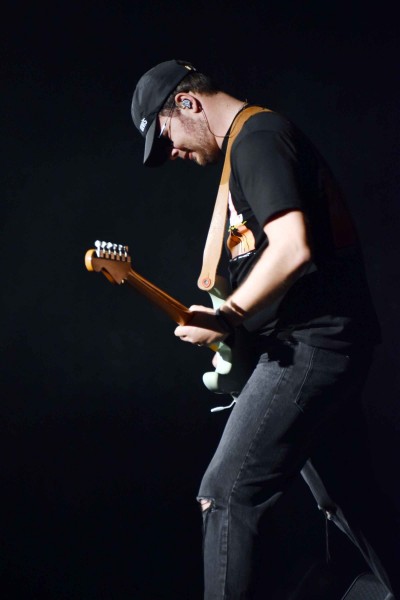 Mężczyzna w czapeczce z daszkiem gra na gitarze eletrycznej