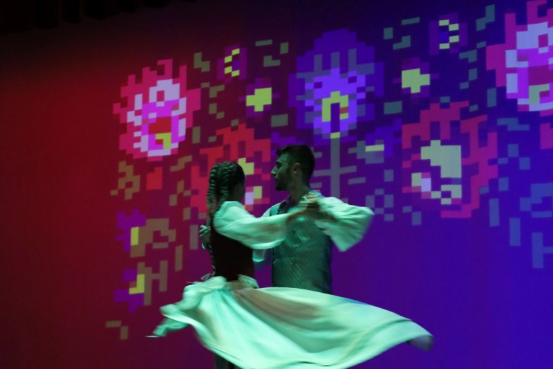 Para tańczy na scenie. Na ścianie kolorowe illuminacje
