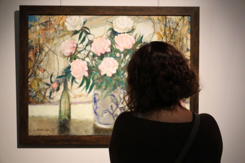Kobieta patrzy na obraz z kwiatami, zdjęcie zrobione z tyłu