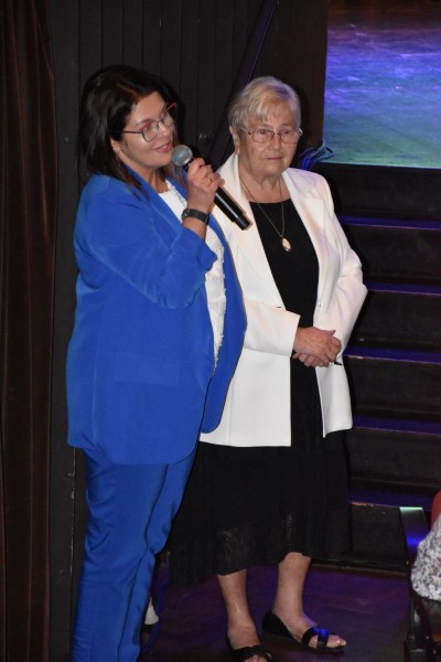 Kobieta w niebieskim garniturze przemawia do zabranych gości